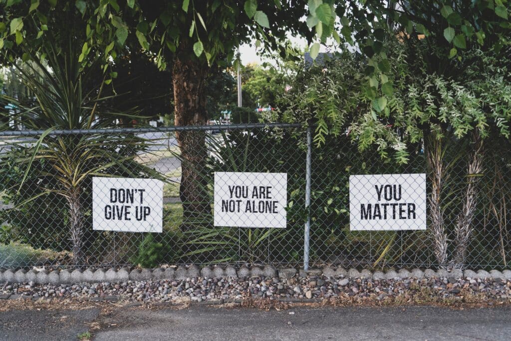 Three posters on fence with trees