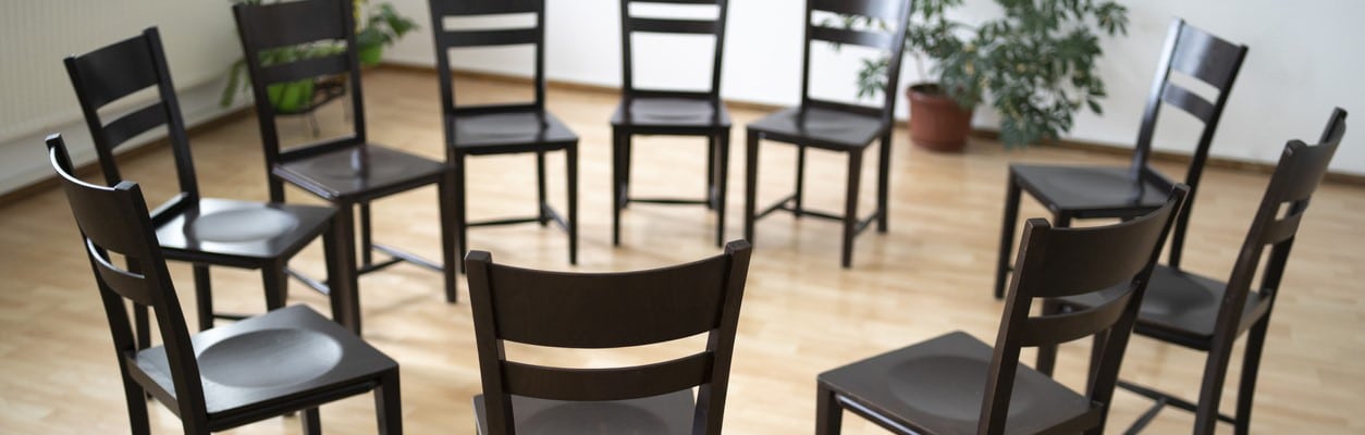 Black chairs arranged in a circle in a rehab group therapy room