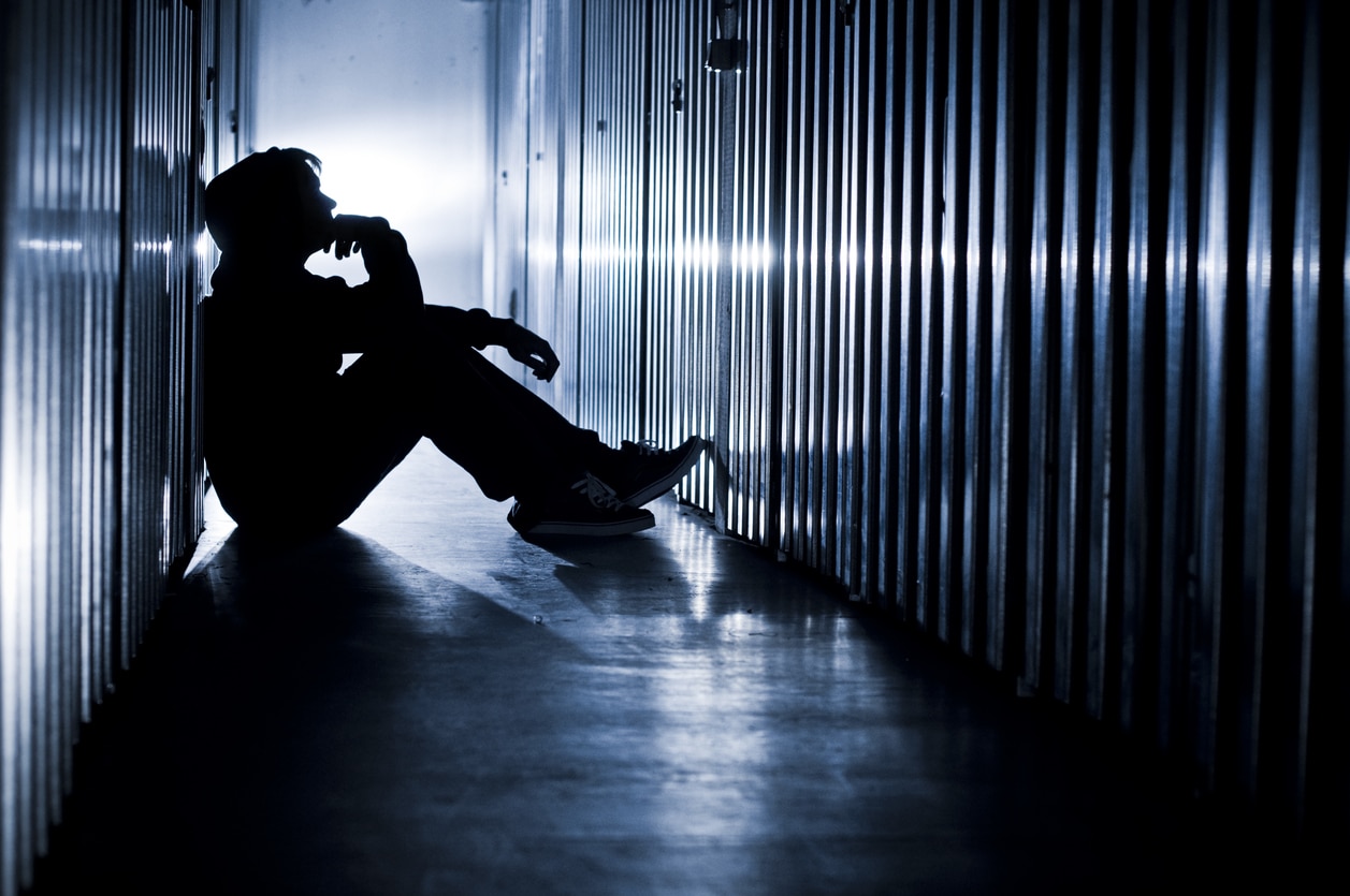 Man with a meth addiction sitting in a dark hallway