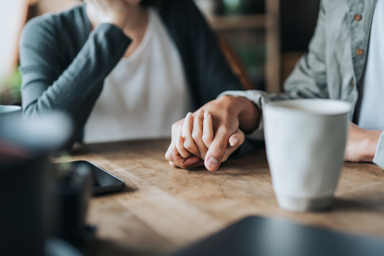 Person in recovery holding hands at a coffee shop table