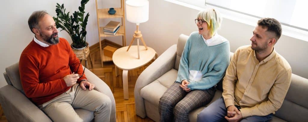 Small group therapy session taking place in a living room at a residential addiction treatment center