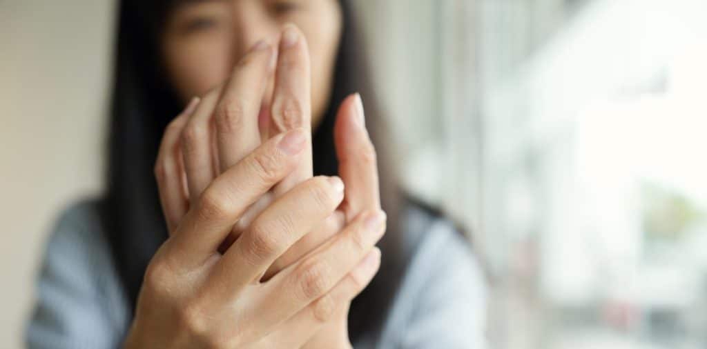 Woman struggling with alcohol addiction holding her weak hand due to neuropathy