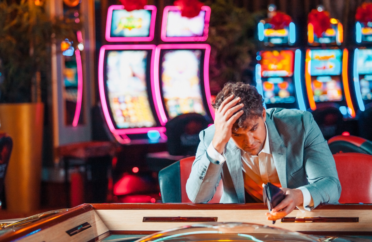 Upset man with gambling addiction sitting at a card table at a casino