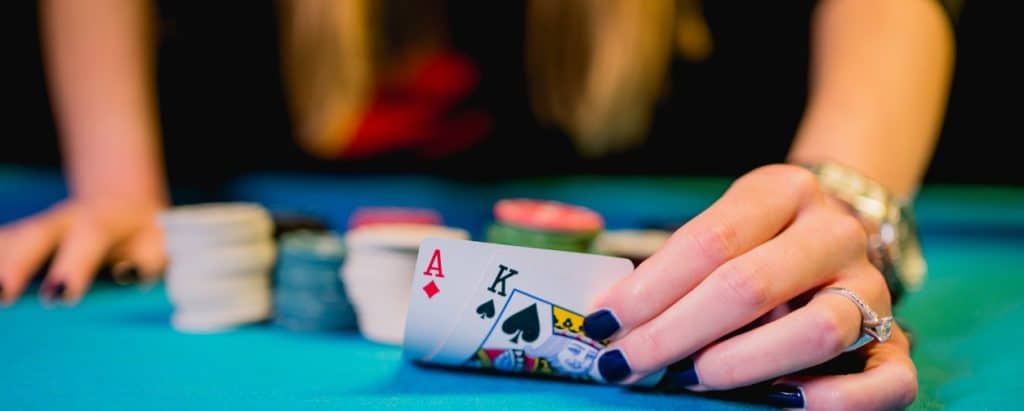 Woman leaning over a poker table with chips in front of her and showing two playing cards