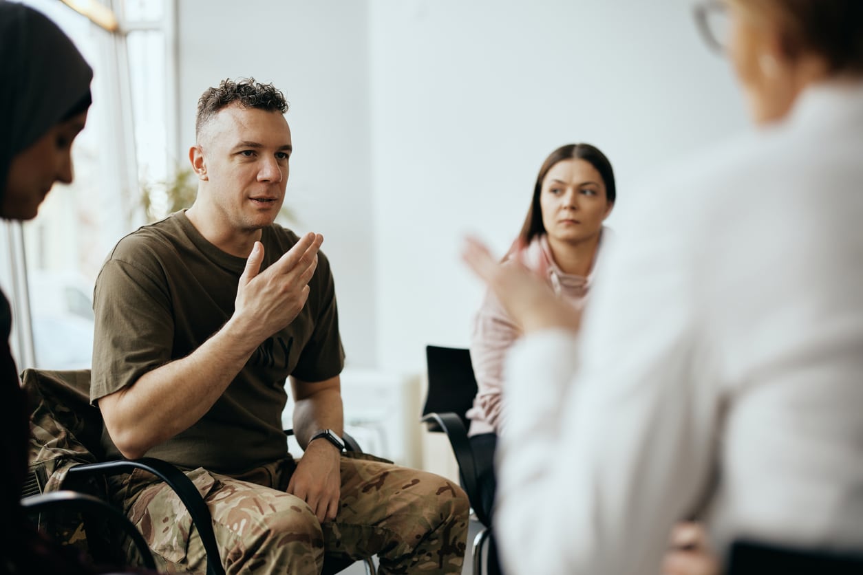 Veteran dressed in casual military clothing talking during a group therapy session